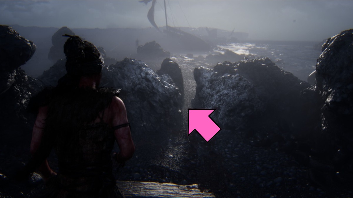 Senua squeezing between two rocks on the shores in Hellblade II